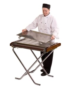 A lady chef adding a tray to the top of the Cinders Classic SG80 Gas BBQ